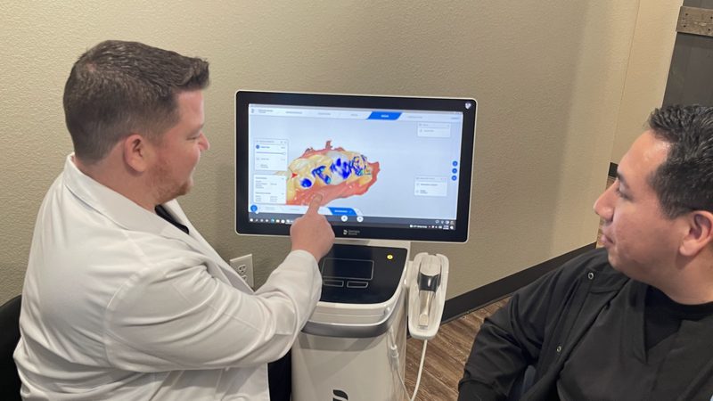 A dentist showing a patient a 3D scan while discussing implant treatment and cost