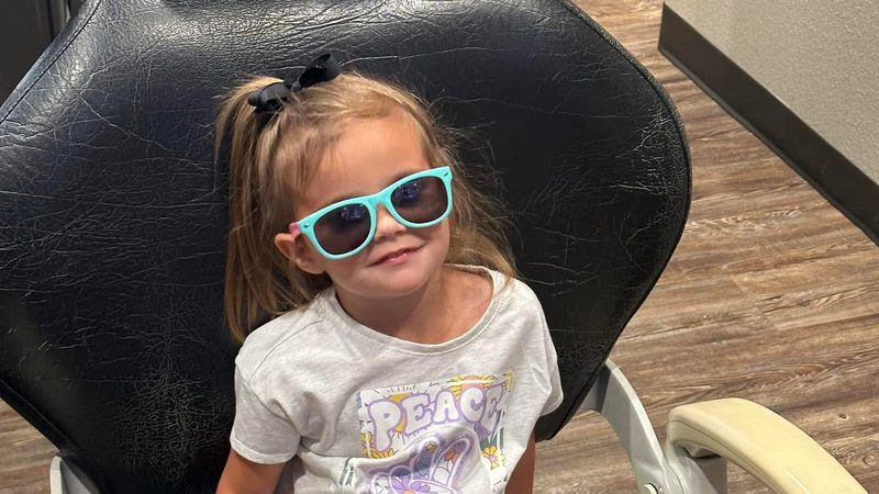 A toddler sitting happily in the dental chair at her first visit