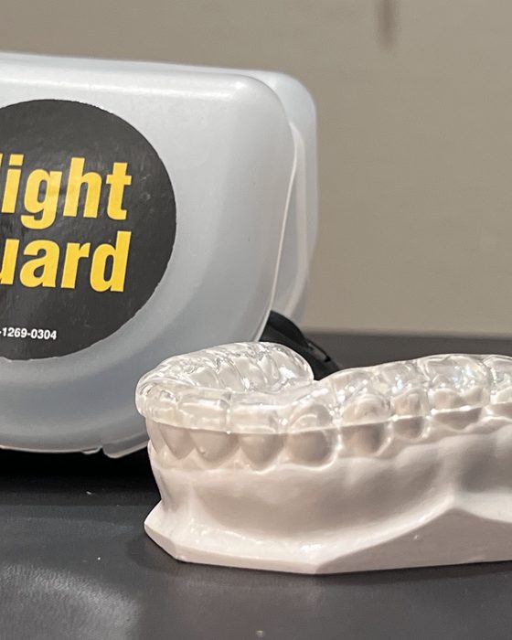 A clear custom night guard resting on a model of a patient's teeth